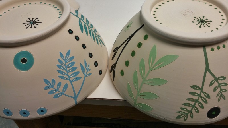 2 ceramic bowls with abstracted plant designs at rest in the studio